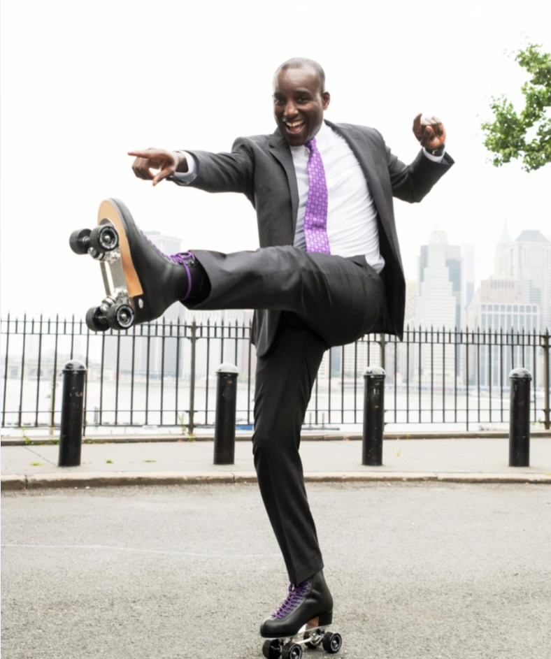 David Isaac roller skating in a suit by the Brooklyn waterfront