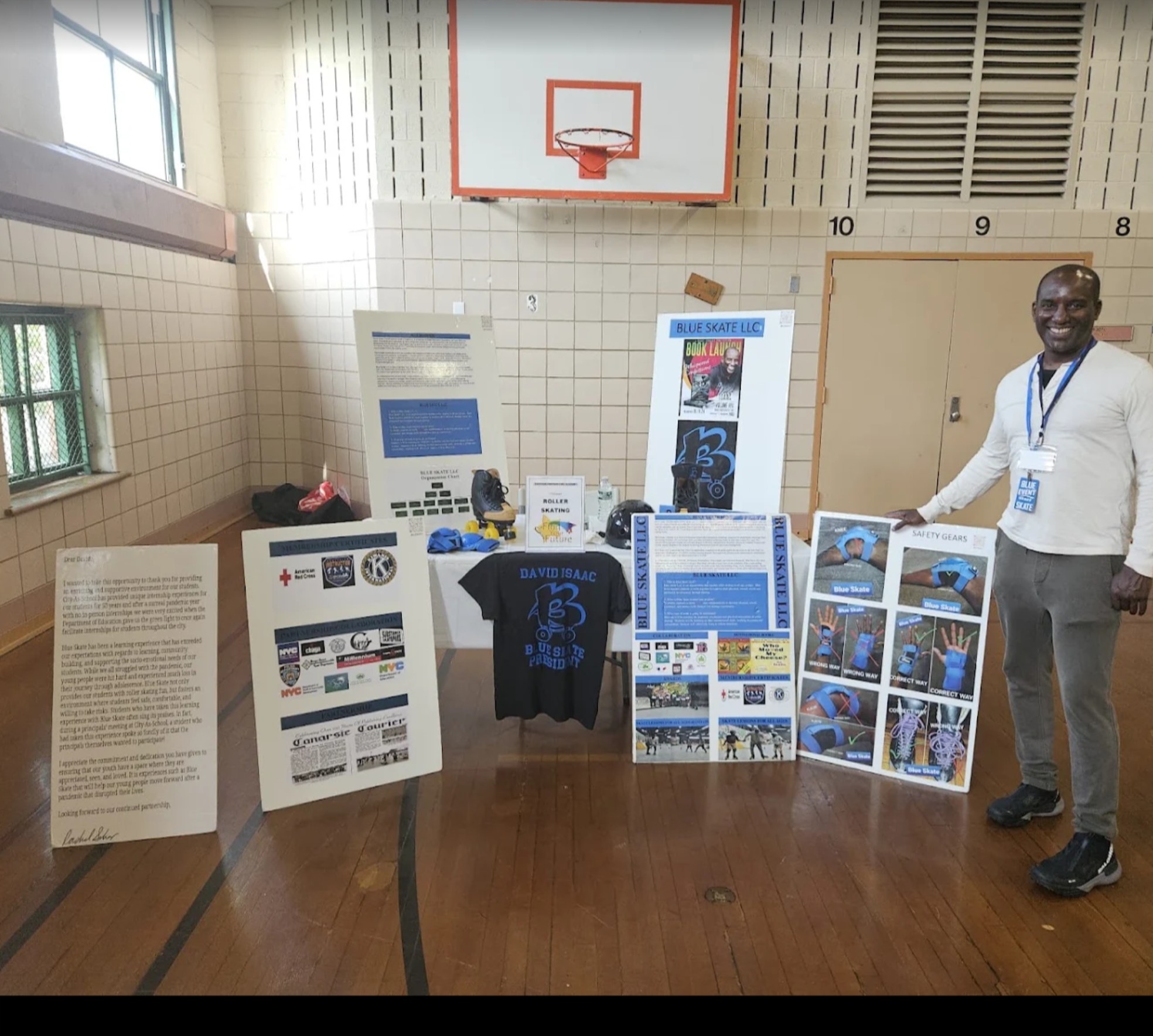 David Isaac presenting the Blue Skate LLC internship program boards at a school gymnasium